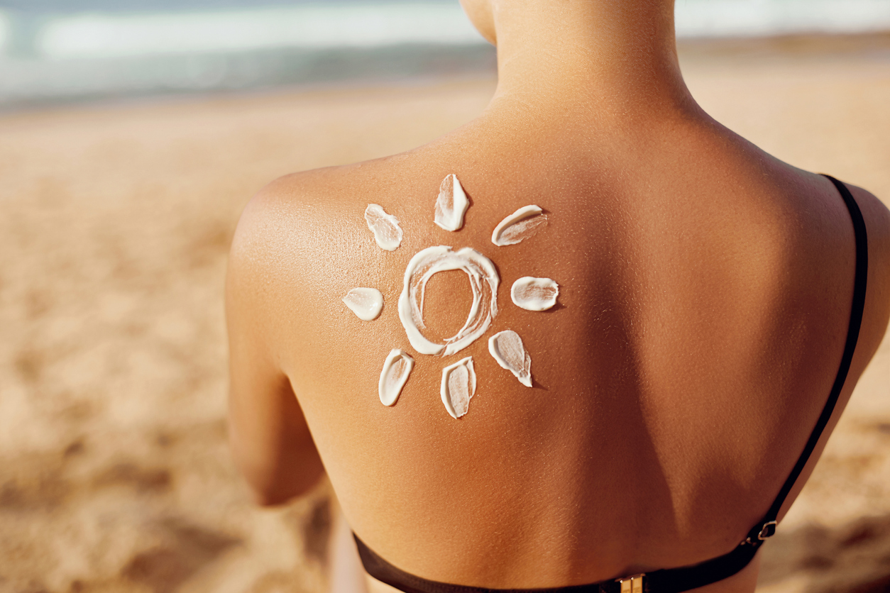 Sunscreen Arranged In The Shape Of The Sun On A Young Woman’s Back At The Shore