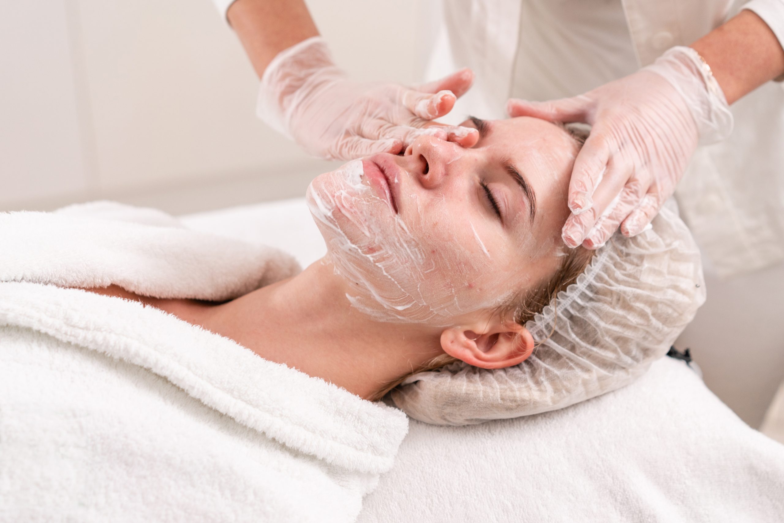 A woman receives topical acne treatment from a professional skincare provider